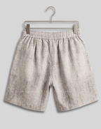 Light beige textured linen shorts with an elastic waistband, hanging on a metal hanger against a solid gray background.