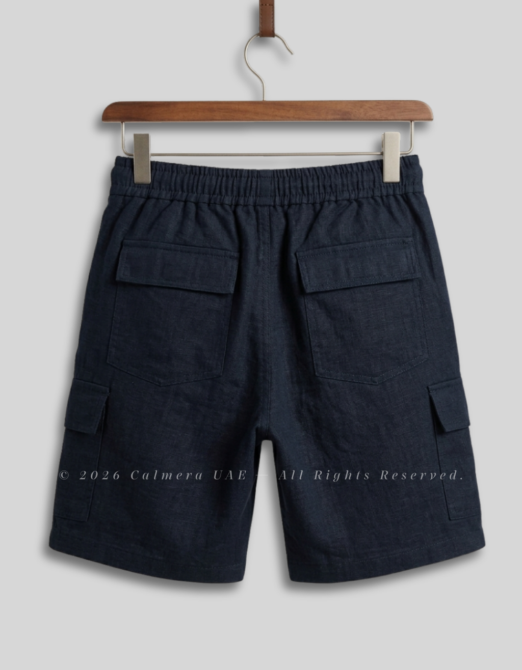 Dark navy blue cargo shorts with an elastic waistband, hanging on a wooden hanger against a light gray background.
