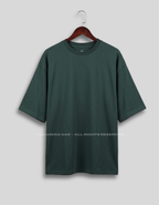 A dark forest green short-sleeve t-shirt hanging on a wooden hanger against a light gray background.