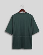 A dark forest green short-sleeve t-shirt hanging on a wooden hanger against a light gray background.